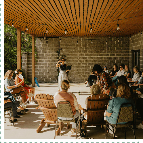 A retreat facilitator speaking to a group of retreat participants in an outdoor patio setting